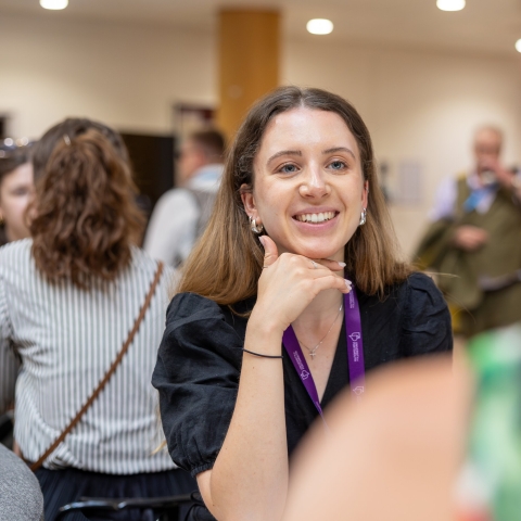 A person smiles while in conversation with another person at an event