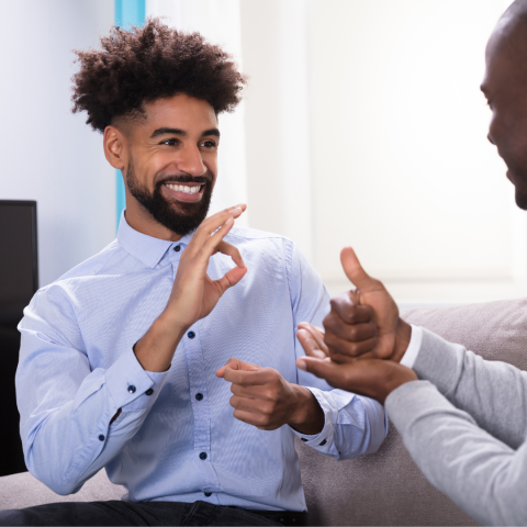 A man in a shirt having a conversation with another person in sign language.