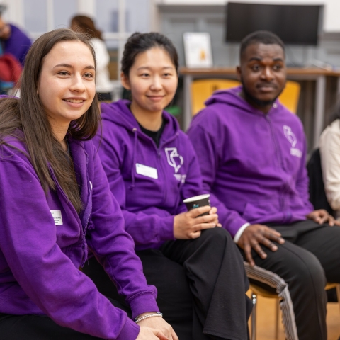 Students sitting together in purple university hoodies