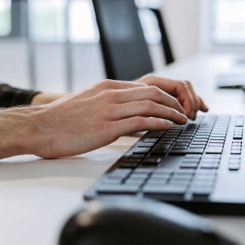 A person's hands typing on computer