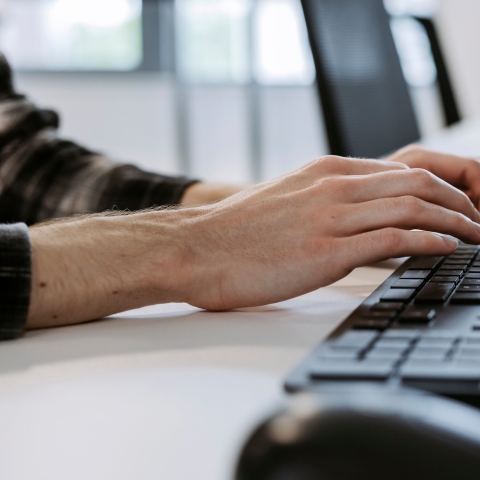 Close-up of hands typing on a laptop keyboard.