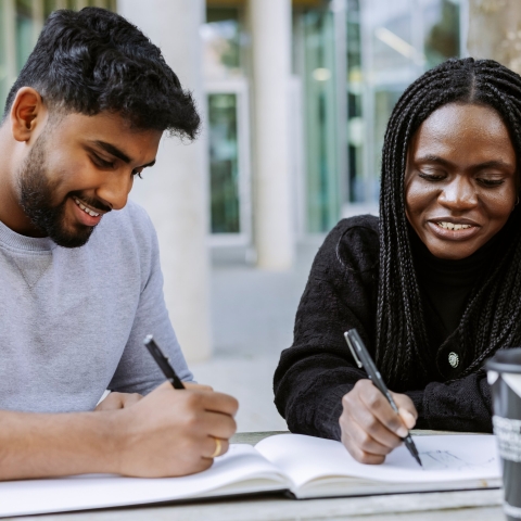 Two students working together from the same book in Eldon seating area