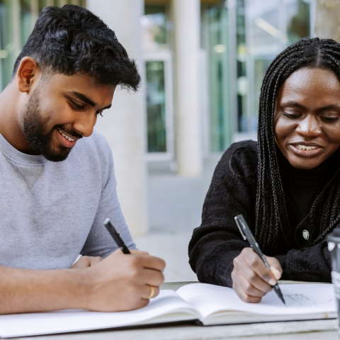Two students working together from the same book in Eldon seating area
