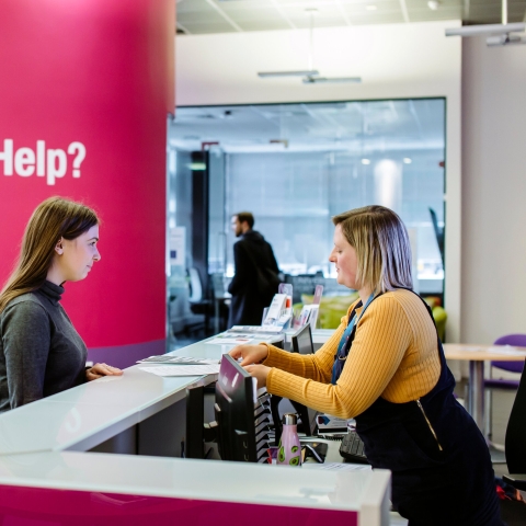 Female student standing at careers and employability help desk