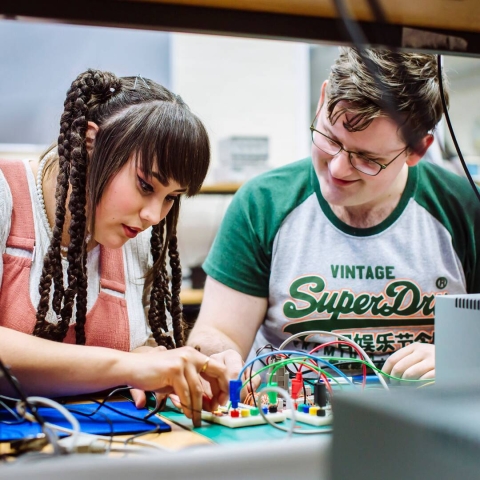 Two students working on electrical circuit board