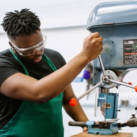 Student wearing goggles and using machinery