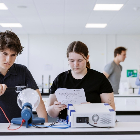 Two students explore electric static properties using a glass orb in the Technology Facilities