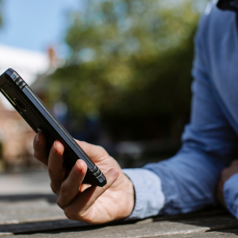 Man's hand holding mobile phone, resting on a table