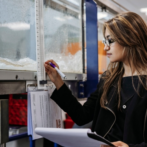 Student measures temperature of container, taking notes in notebook at Technology Facilities