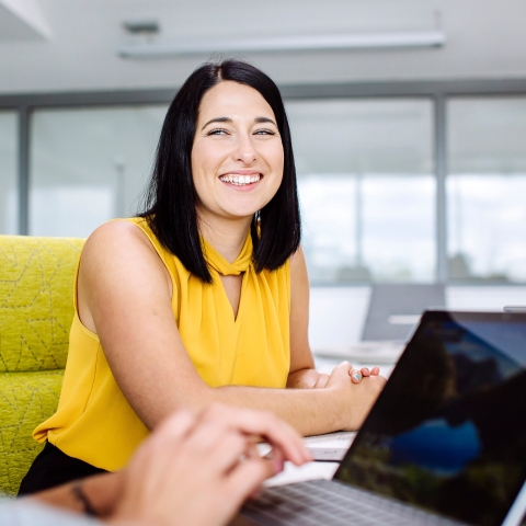 Student sat in chair smiling at another person