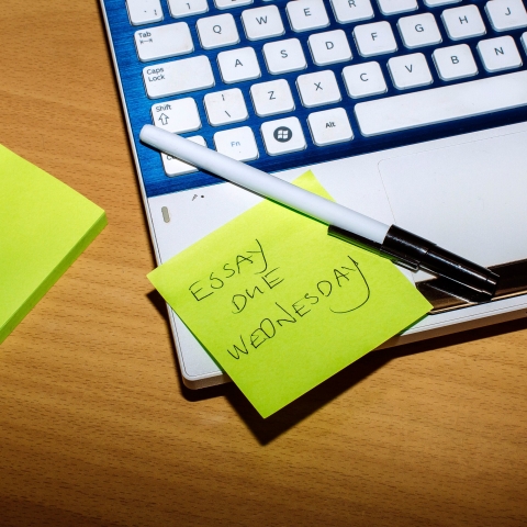 Laptop open with sticky notes showing essay deadlines