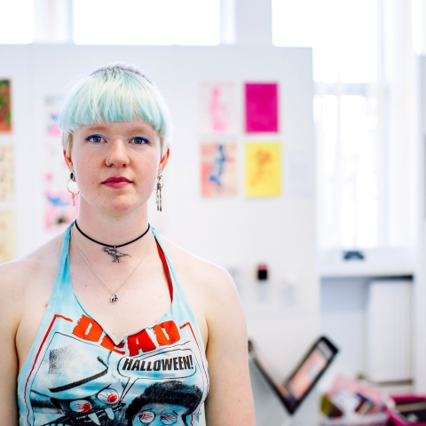 A woman with blue hair standing in front of artwork