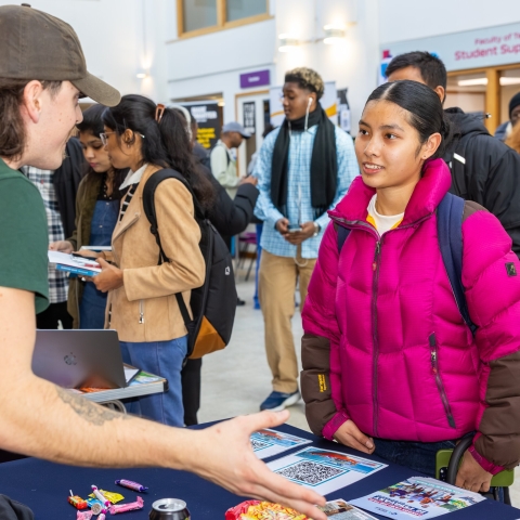 An employer enthusiastically talking to a student at a career fair. 