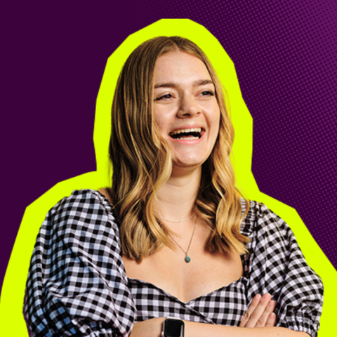 A picture of a girl looking off camera and laughing. The background is dark purple.