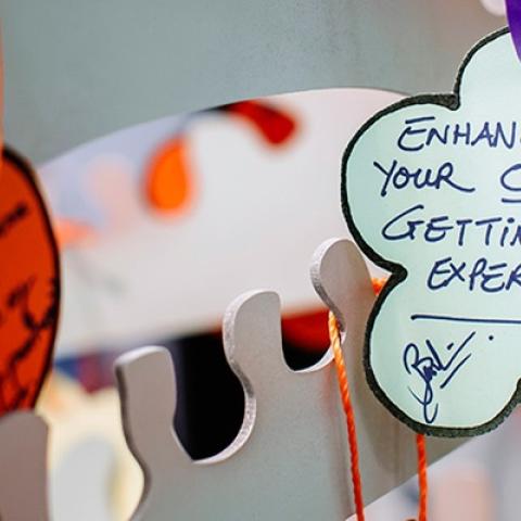 Person hanging up label in the shape of a flower with writing on it about work experience at the volunteering fair
