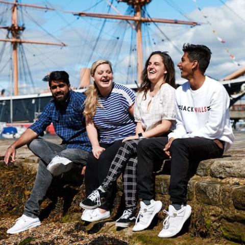 Four University of Portsmouth students laughing at historic dockyard