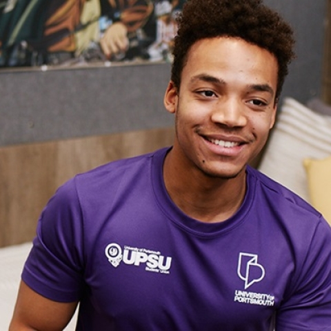 Male residence life assistant smiling and sitting in room