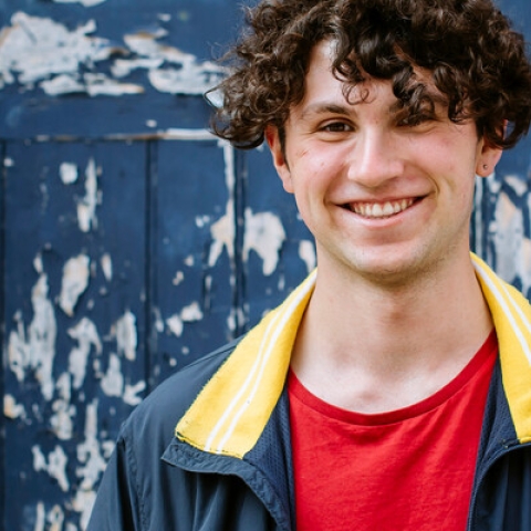 Student smiling in blue jacket with red shirt
