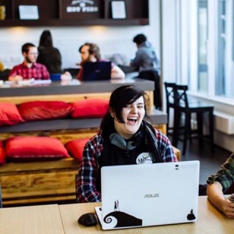 A student laughing with a laptop on her lap