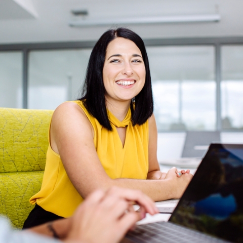 Student sat in chair smiling at another person