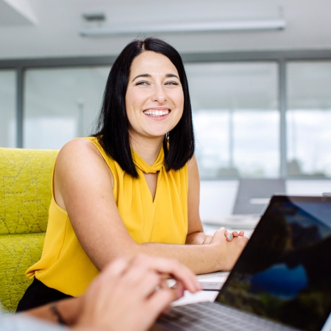 Student sat in chair smiling at another person