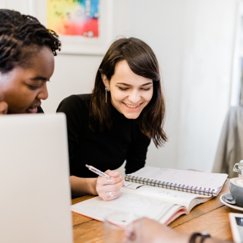 students smiling over coffee at a desk