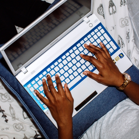 Student using laptop to complete university work in halls bedroom