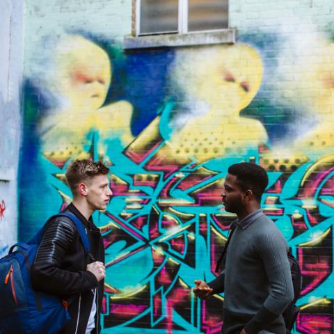 Two students talking in front of graphic painted on wall