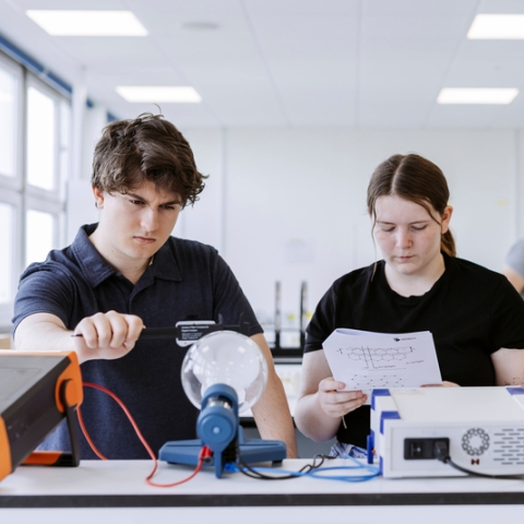 Two students explore electric static properties using a glass orb in the Technology Facilities