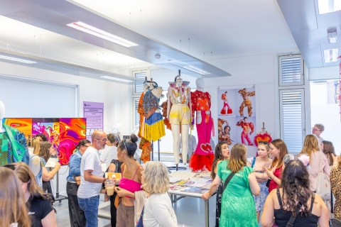 image from grad show 2025 of people standing in fashion studio looking at work