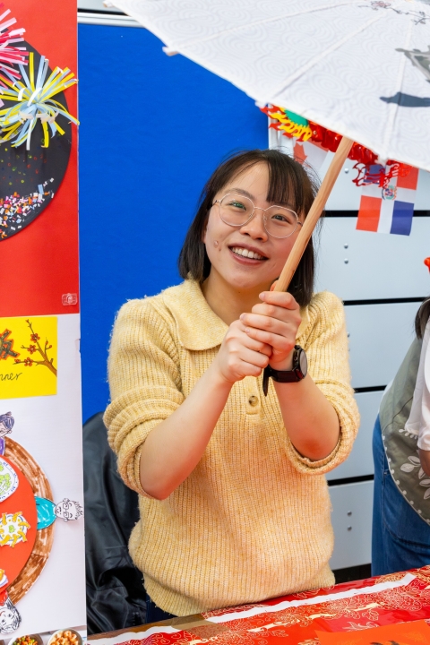 A smiling student is holding a Chinese parasol