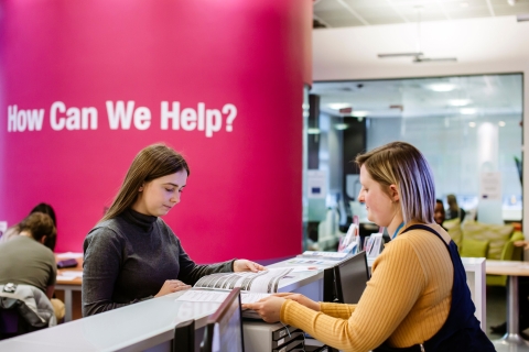 Careers adviser showing a student some resources at the front desk of the careers centre