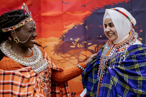 Student in traditional Kenyan attire smiling with another student