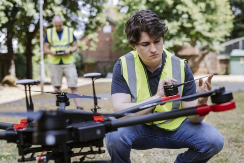 Male student in hi-vis vest testing drone