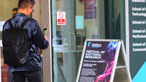 A festival delegate reading the festival sign board outside Eldon Building