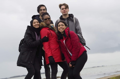 Five international students standing on the beach in winter in Portsmouth