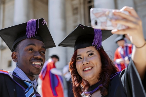 Male and female student taking a selfie at graduation