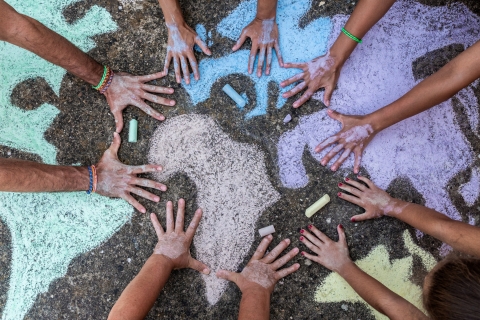 Hands on pavement graffitied with chalk