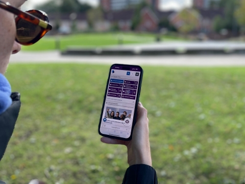 Student holding a mobile device with new MyPort homepage displaying on screen