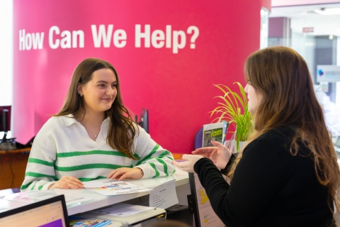 Student standing at front desk talking to a careers advisor 