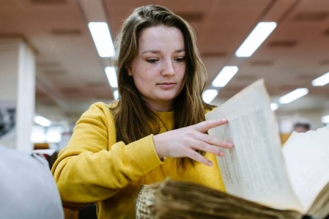 female student flipping through book in library