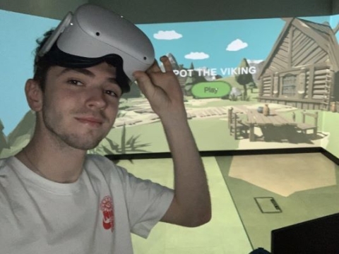 Jake wearing VR headset in the background of virtual Viking village