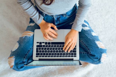 Student sat cross legged with a laptop