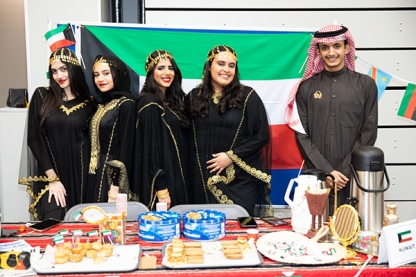 Students posing in front of the flag of Kuwait