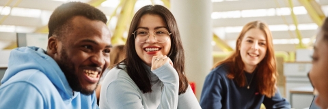 Three undergraduate students laughing while chatting