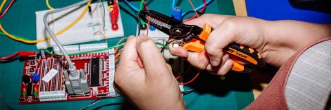 Close up of hands using wire cutters to cut an electrical cable