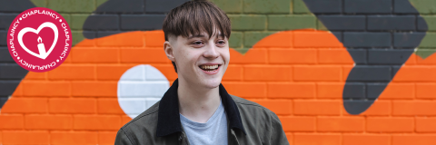 Chaplaincy hero image showing a smiling student standing in front of a colourful wall