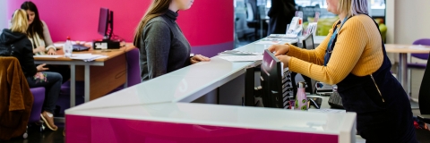 Female student standing at careers and employability help desk