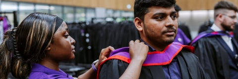 Woman helping a graduate adjust their graduation robe