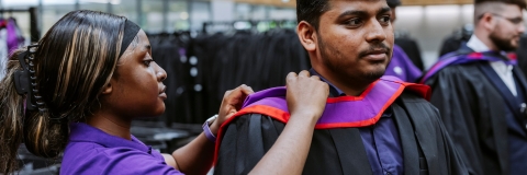 Woman helping a graduate adjust their graduation robe